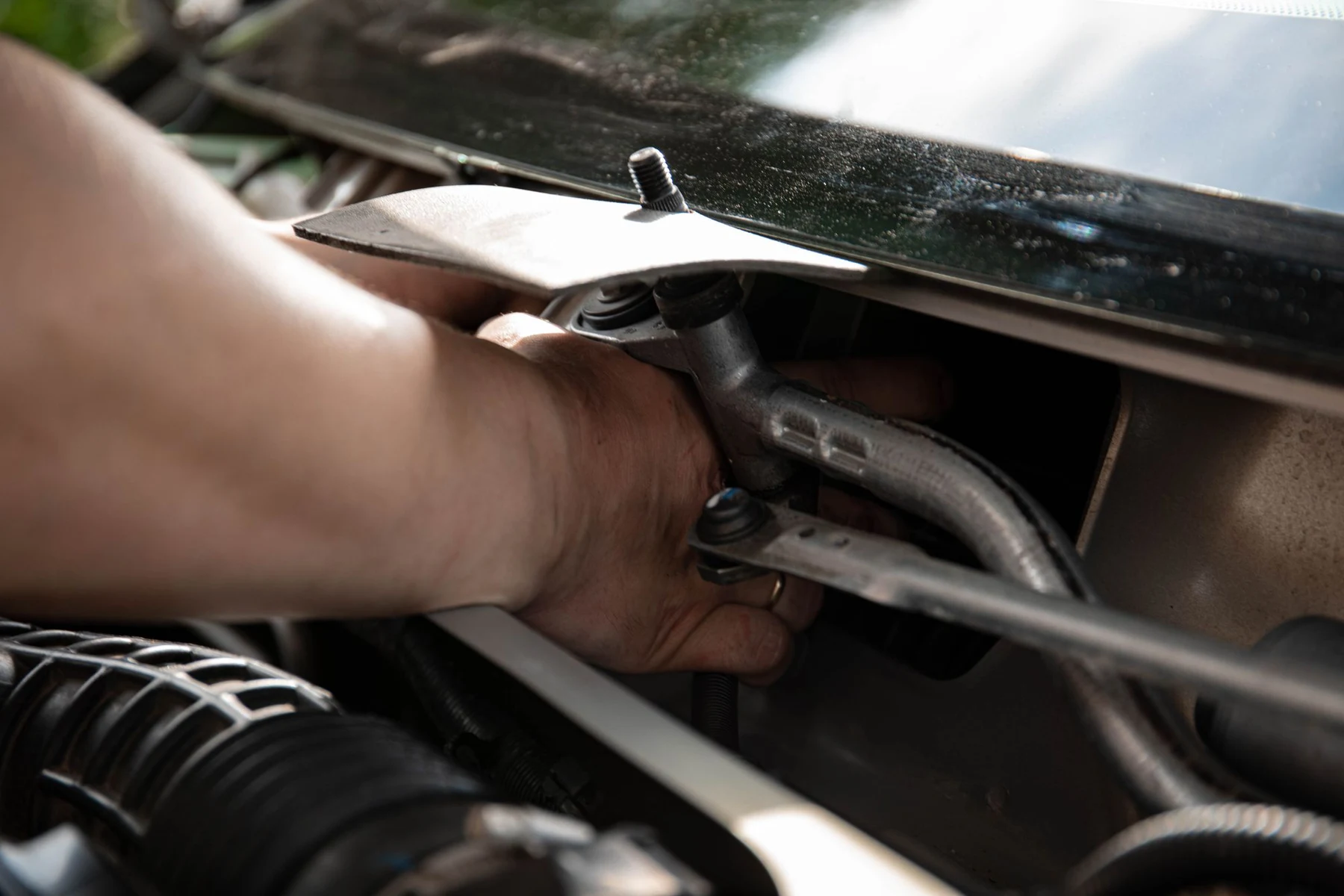 Ruke mehaničara pri popravci automobila